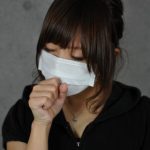 マスクで咳払いする女性